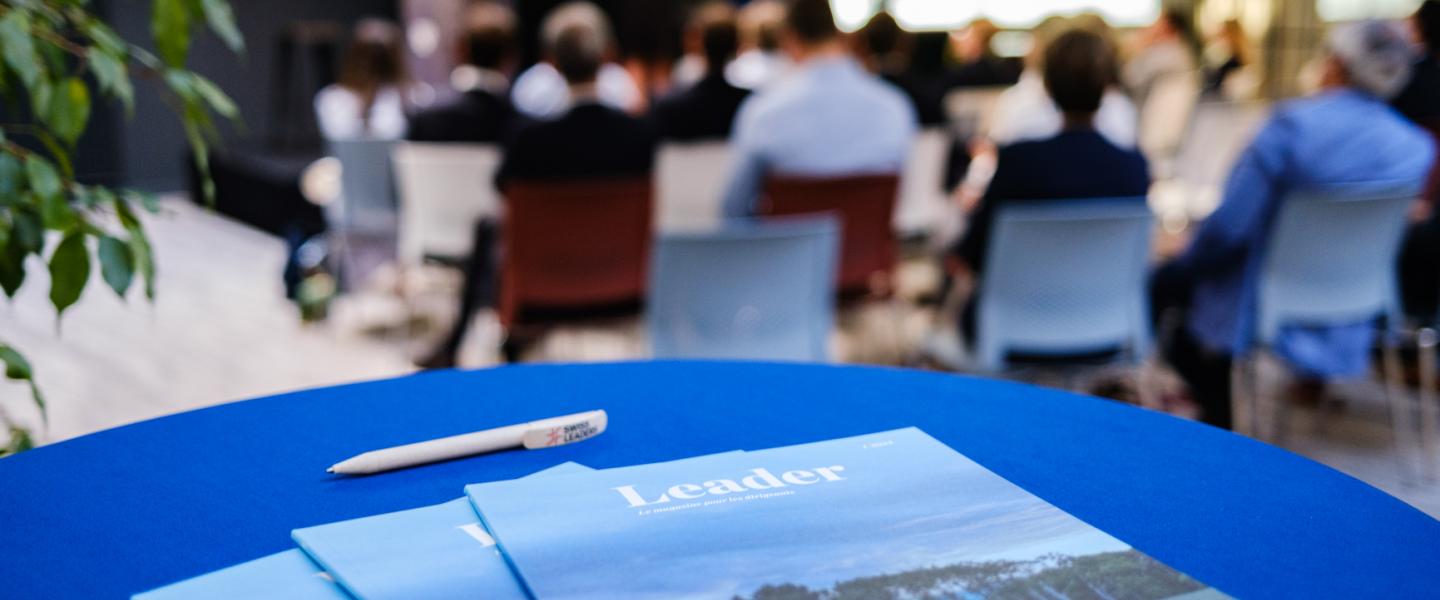 Leader Mag im Vordergrund, Personen im Workshop im Hintergrund.
