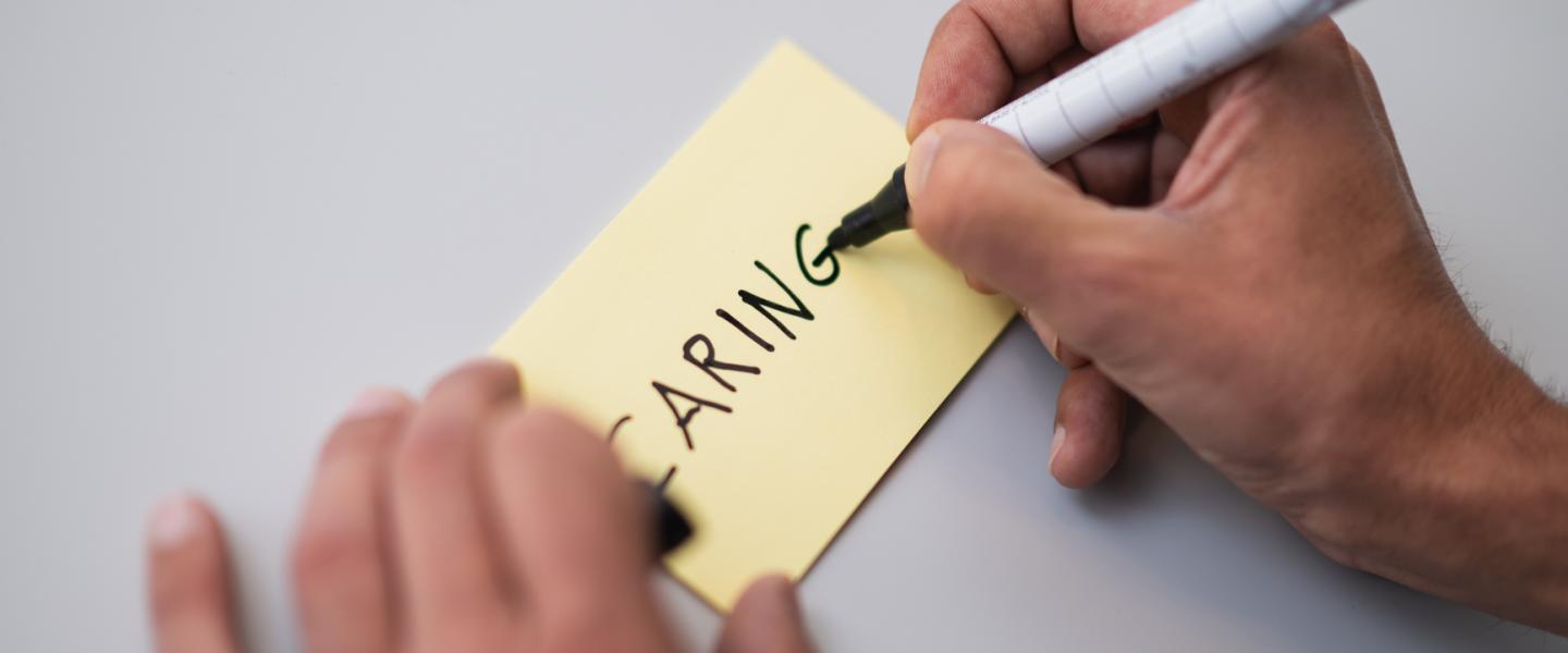 Le mot «Caring» écrit sur un post-it jaune