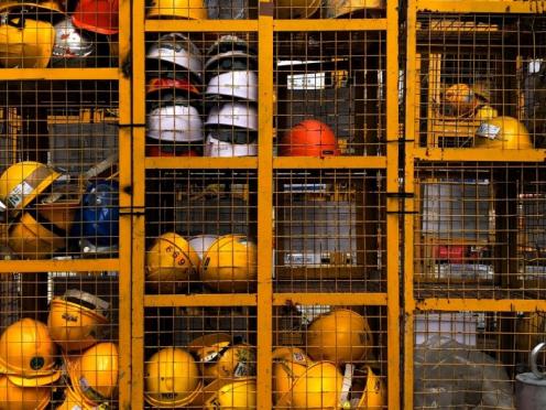 Casques de protections majoritairement jaunes dans une cage.