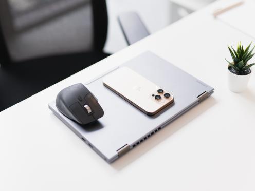 Ordinateur portable fermé avec téléphone et souris sur un bureau.