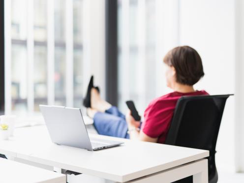 Personne assise au bureau, téléphone à la main