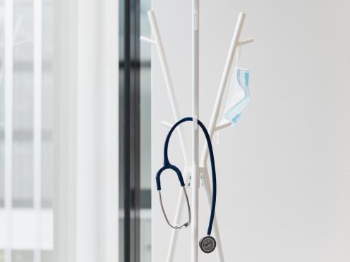 Stéthoscope et masque suspendus à une patère.