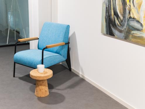 Fauteuil bleu avec une petite table basse à côté d’un tableau.