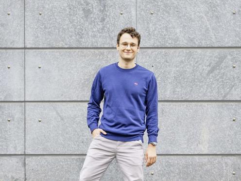 Gaël Riesen in Ganzkörperaufnahme, mit einem blauen Pullover und lächelnd.