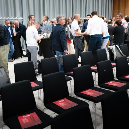 Leader-Magazin auf Stühlen, Menschen im Hintergrund.