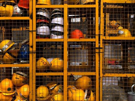 Casques de protections majoritairement jaunes dans une cage.