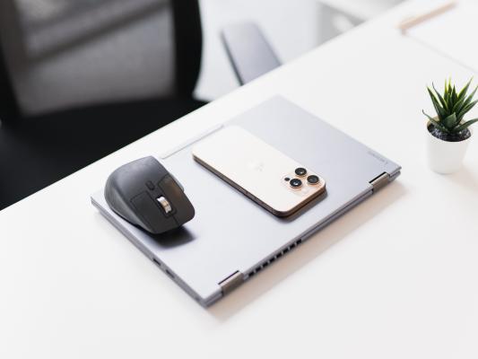 Geschlossener Laptop mit Handy und Maus auf einem Schreibtisch.