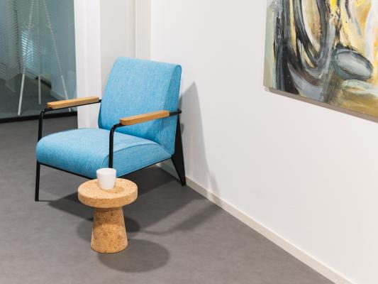 Fauteuil bleu avec une petite table basse à côté d’un tableau.