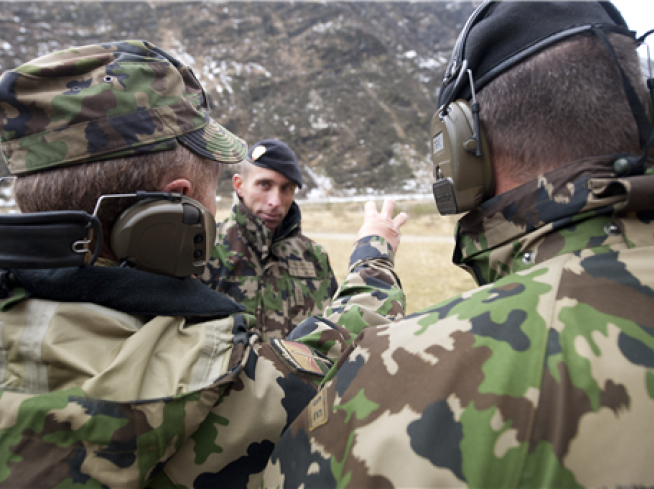 Trois officiers de l’Armée suisse, dont deux vus de dos.