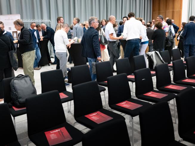 Leader-Magazin auf Stühlen, Menschen im Hintergrund.