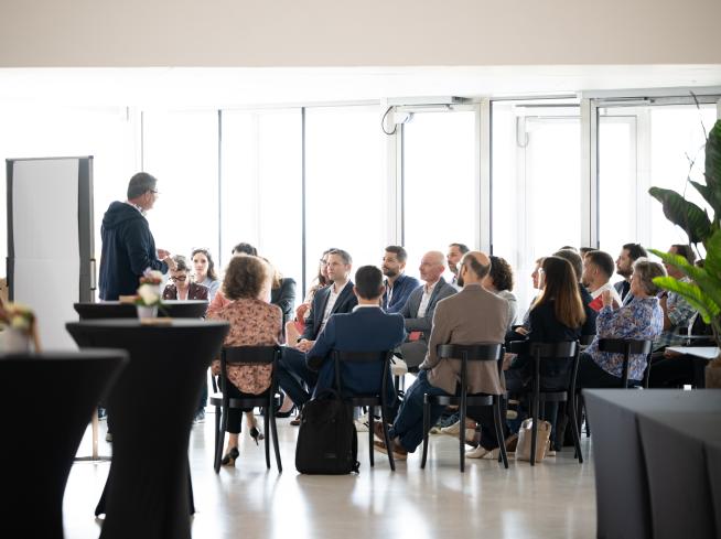 Persone sedute ascoltano una persona che conduce un workshop.