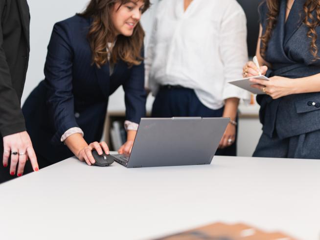 Quattro persone lavorano insieme a un laptop.