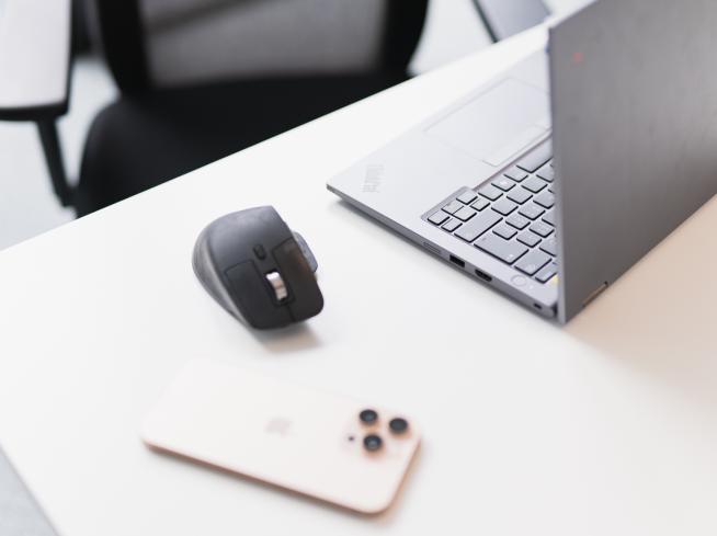 Smartphone à côté d’un ordinateur portable ouvert et d’une souris.
