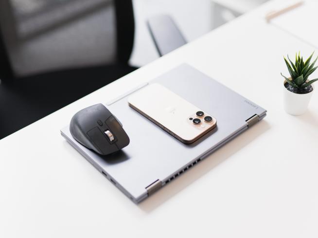 Laptop chiuso con telefono e mouse su una scrivania.