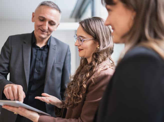 Tre persone discutono attorno a un tablet.
