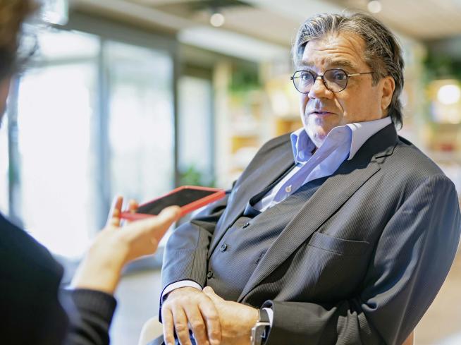 Ritratto di Antoine Hubert seduto mentre parla in un ambiente interno.